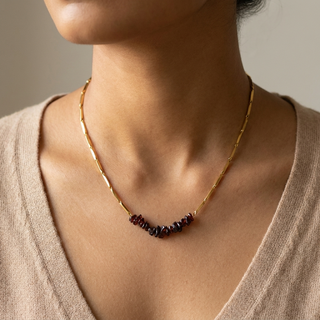 Necklace worn close on a woman's neckline showing the garnet cluster resting at the base of the neck