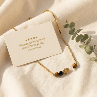 Necklace beside a five-star review card in a warm lifestyle setting